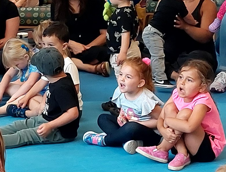 Kids sitting on a floor excited to hear a story