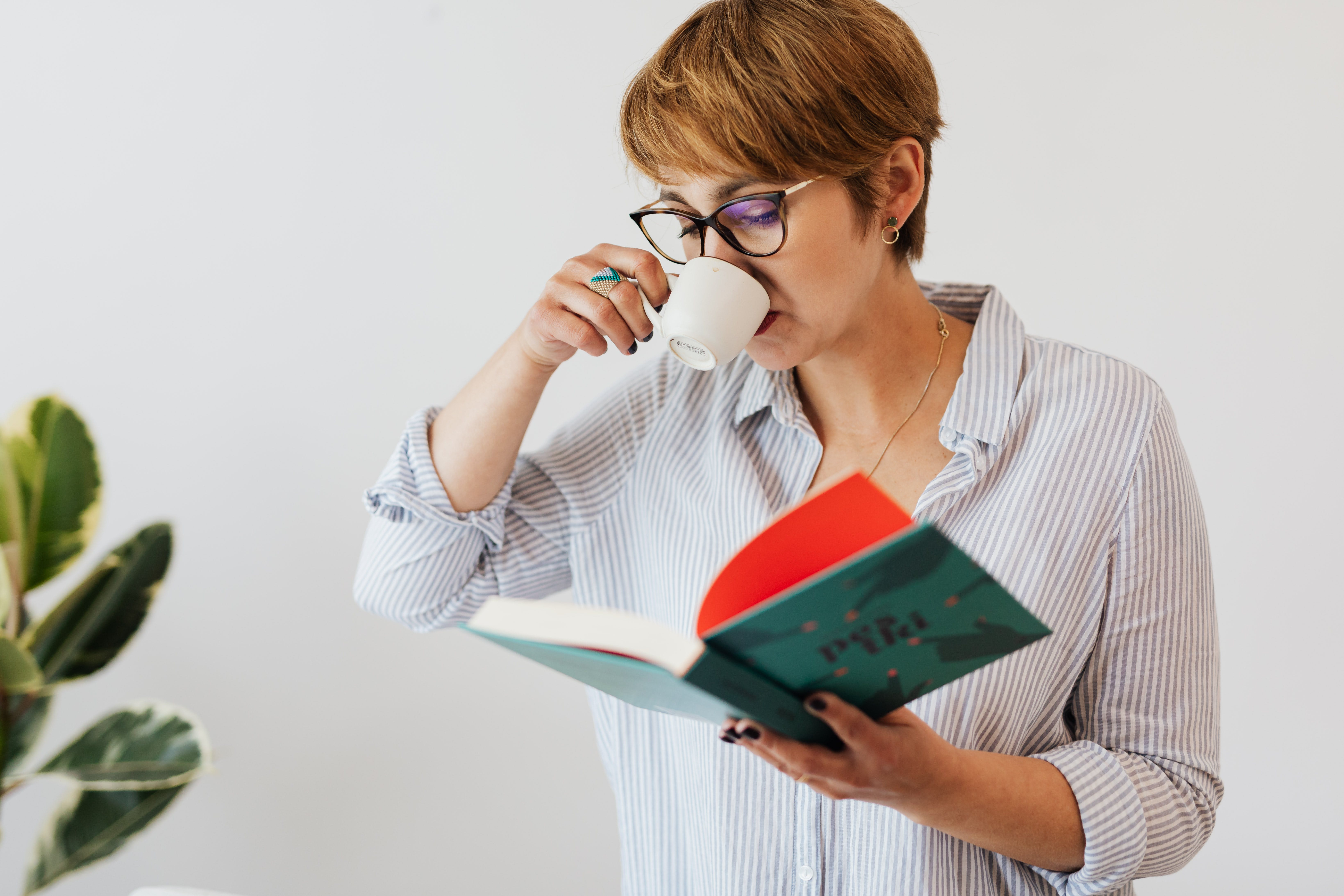 A Woman Drinking an Espresso and Reading a Book