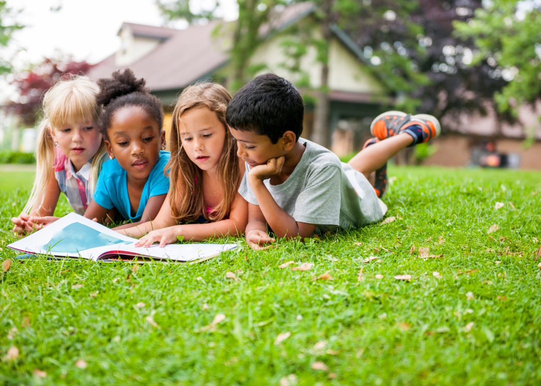 Children reading a book together outside
