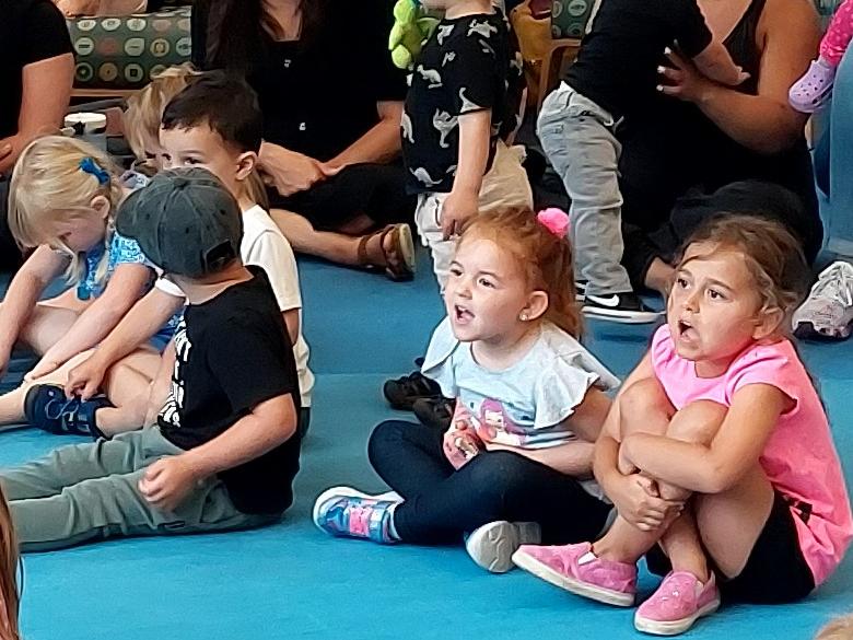 Kids sitting on a floor excited to hear a story