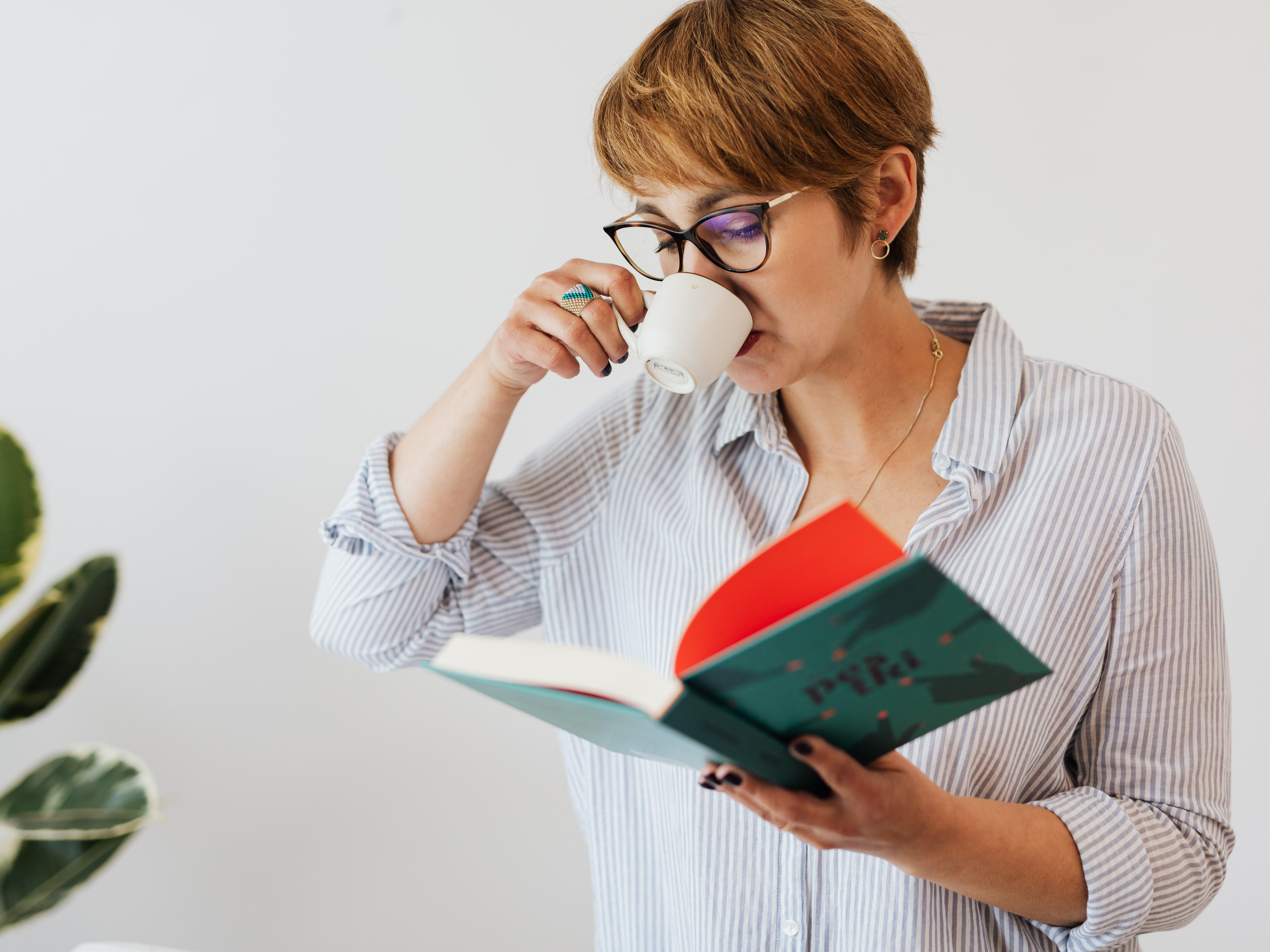 A Woman Drinking an Espresso and Reading a Book