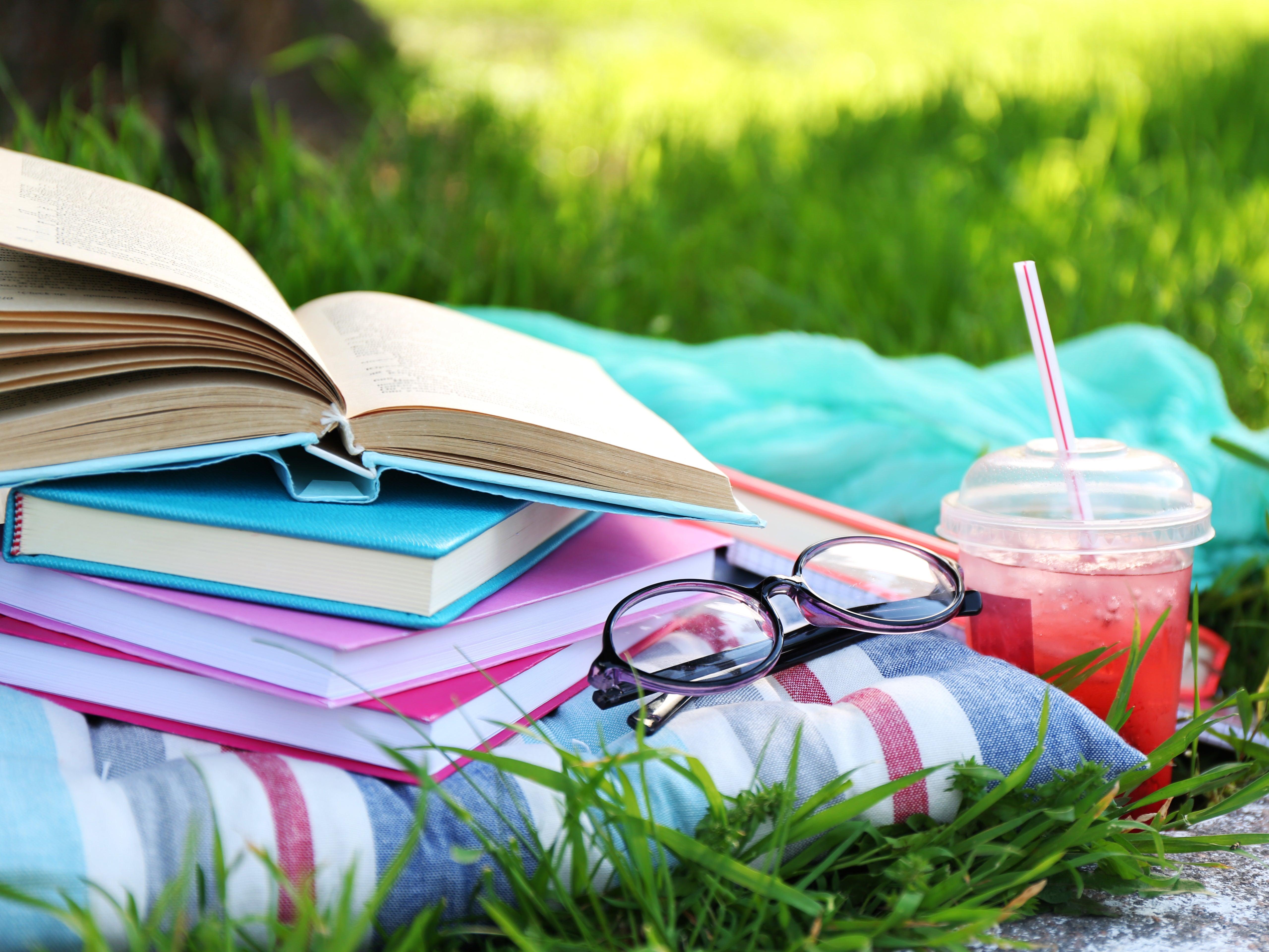 books and glasses on a blanket with pink drink