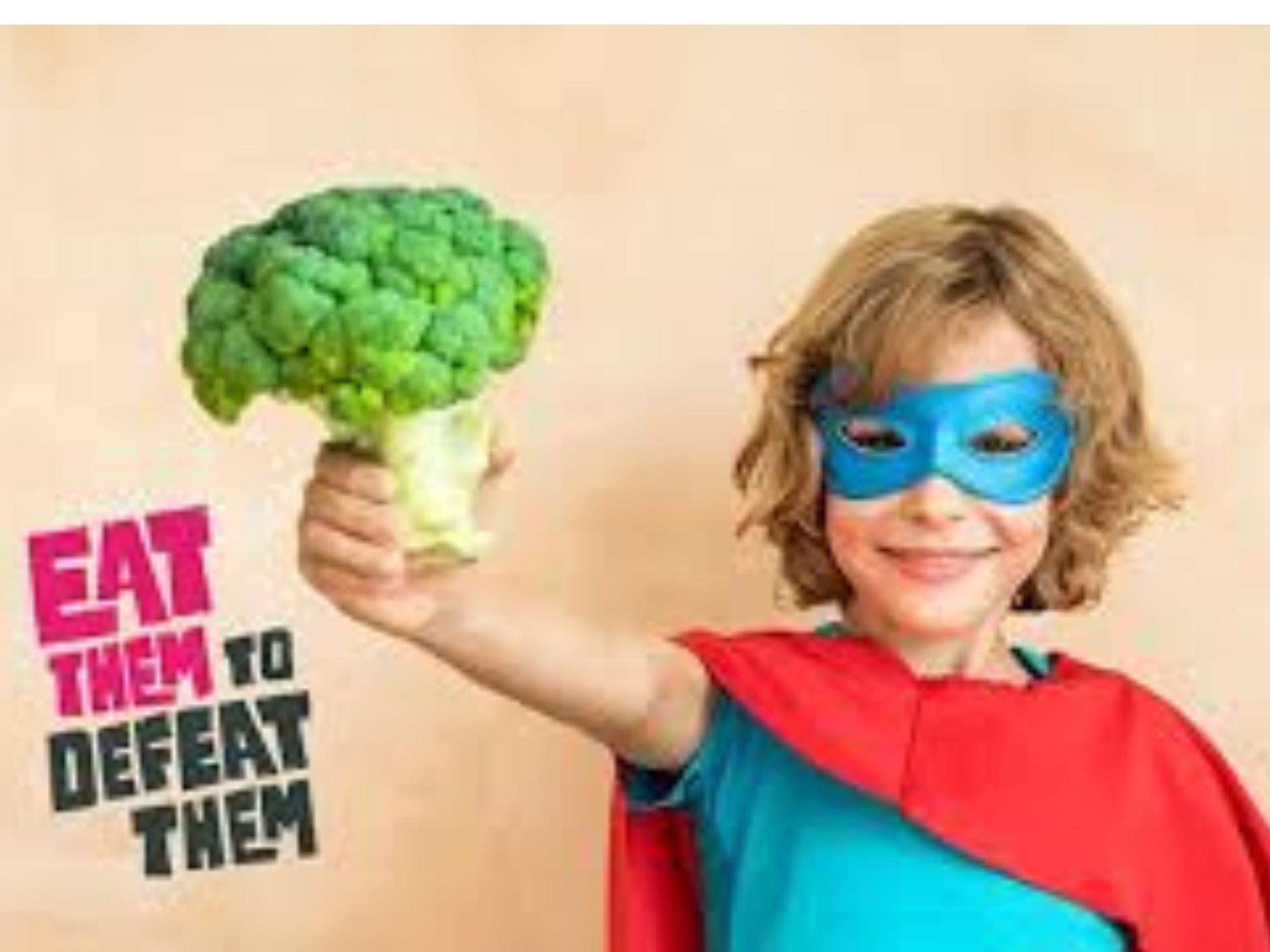 Child with superhero mask holding broccoli