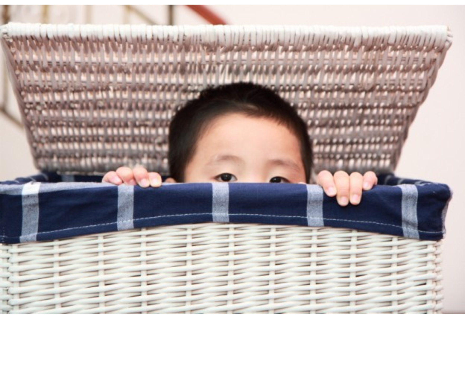 kid peeking from laundry basket